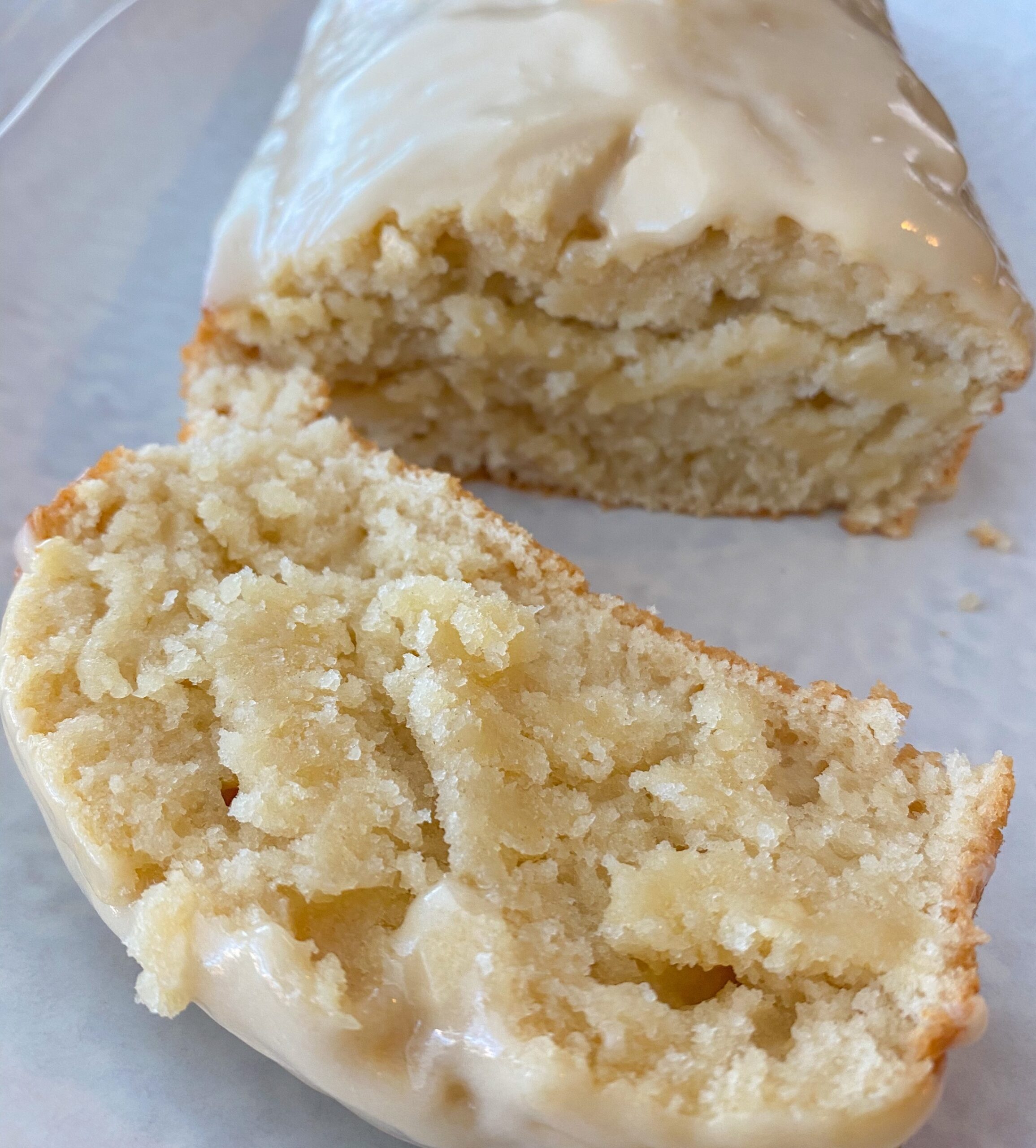 Lemon cake on a white plate with one slice cut off the end. 