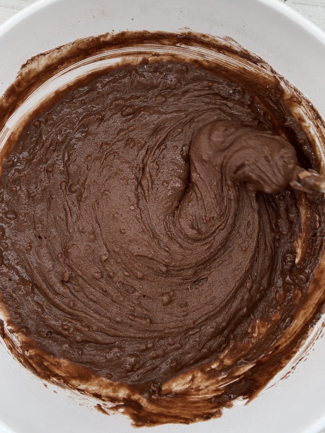 cake batter being mixed with a fork in a white bowl. 