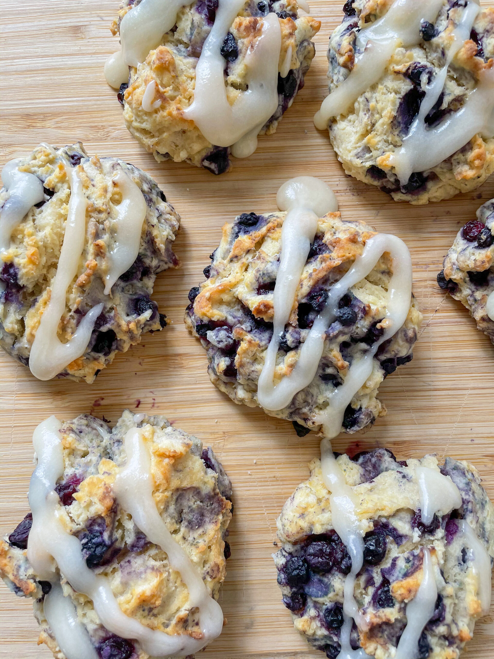 Vegan blueberry biscuits on a wooden cutting board with a glaze on top. 