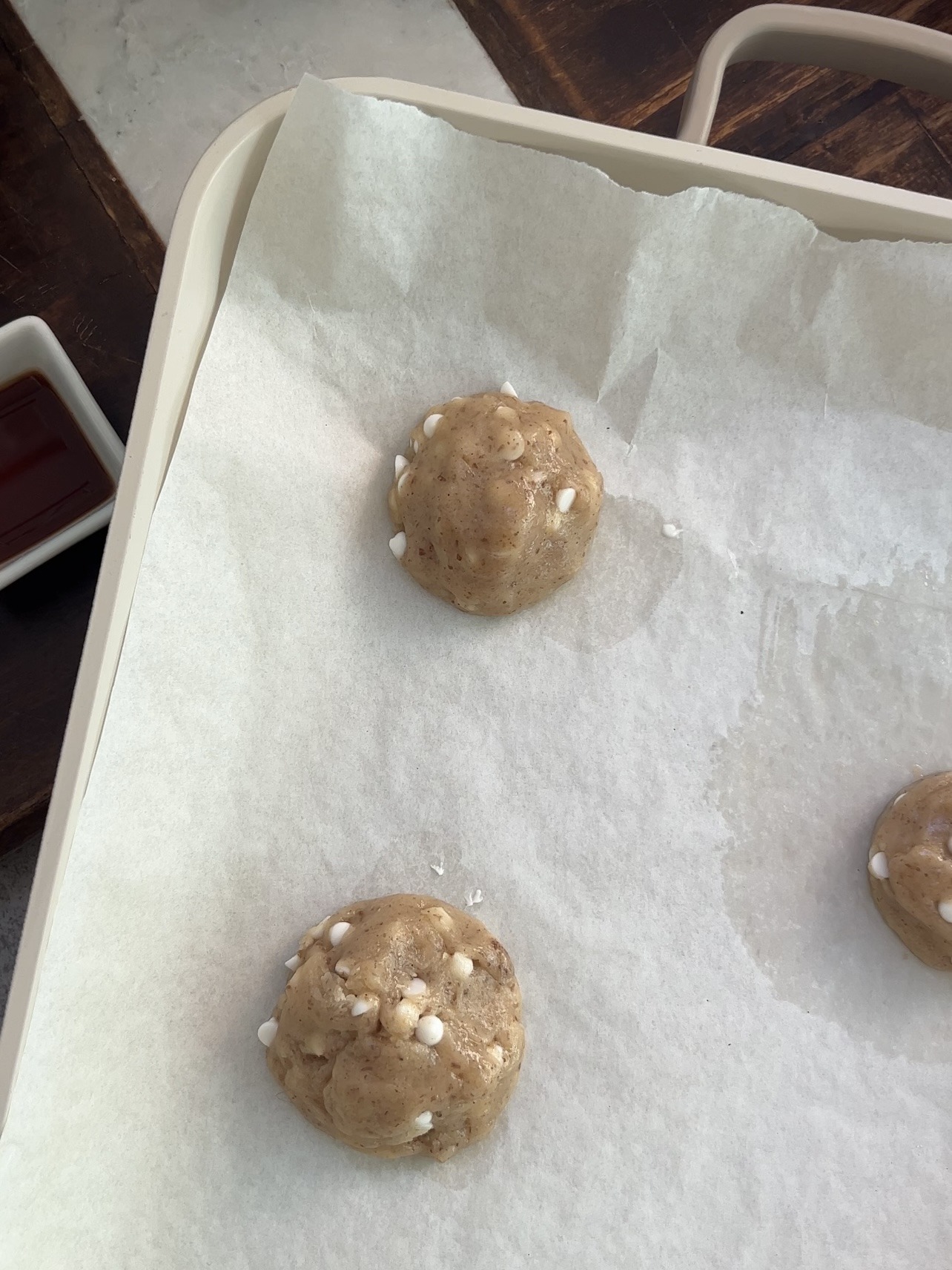 white chocolate chip cookie dough balls on lined baking sheet