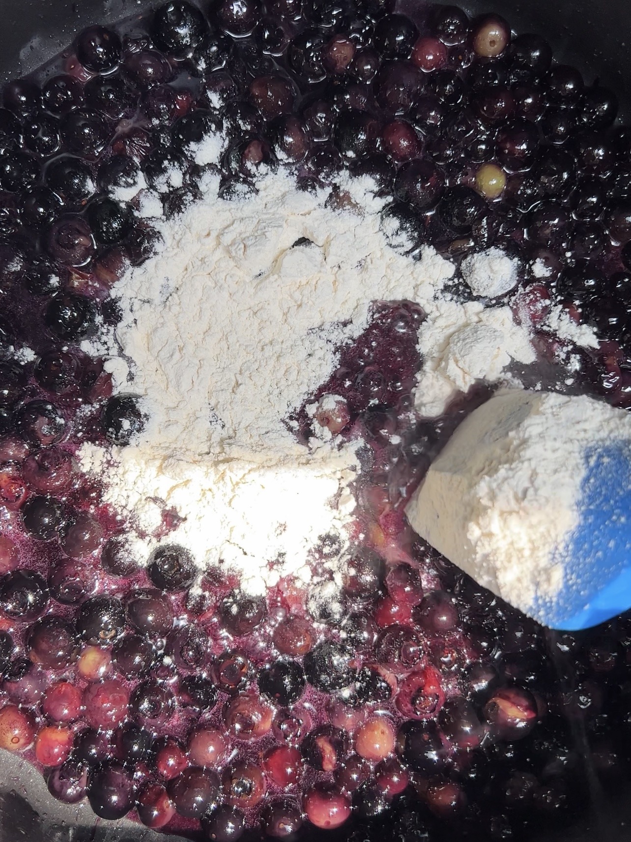 making the blueberry cobbler filling by cooking the blueberries, sugar, flour, and butter together on the stovetop.