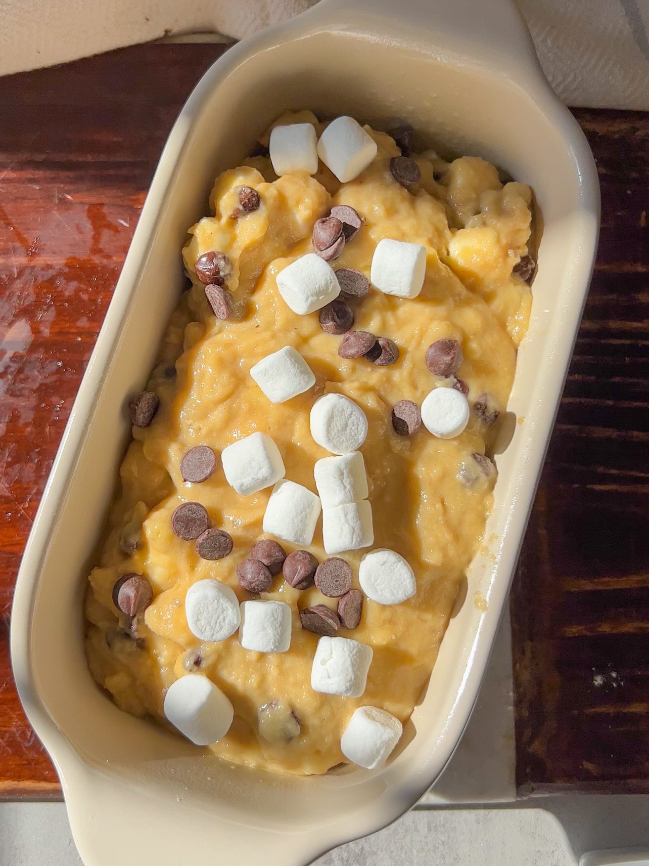 smores banana bread - adding the batter to the loaf pan and then topping with chocolate chips and marshmallows