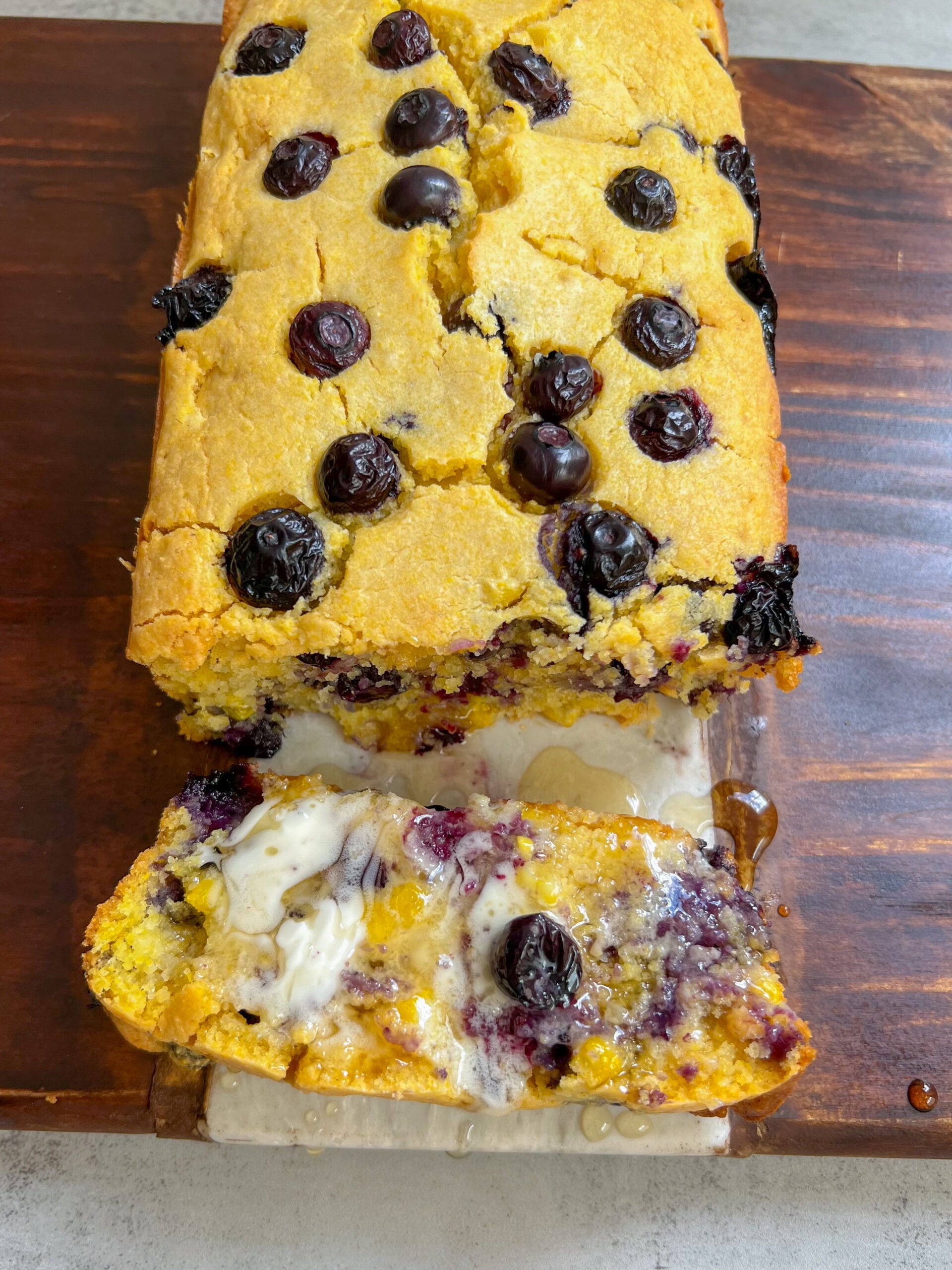 blueberry cornbread spread with butter and drizzled with agave