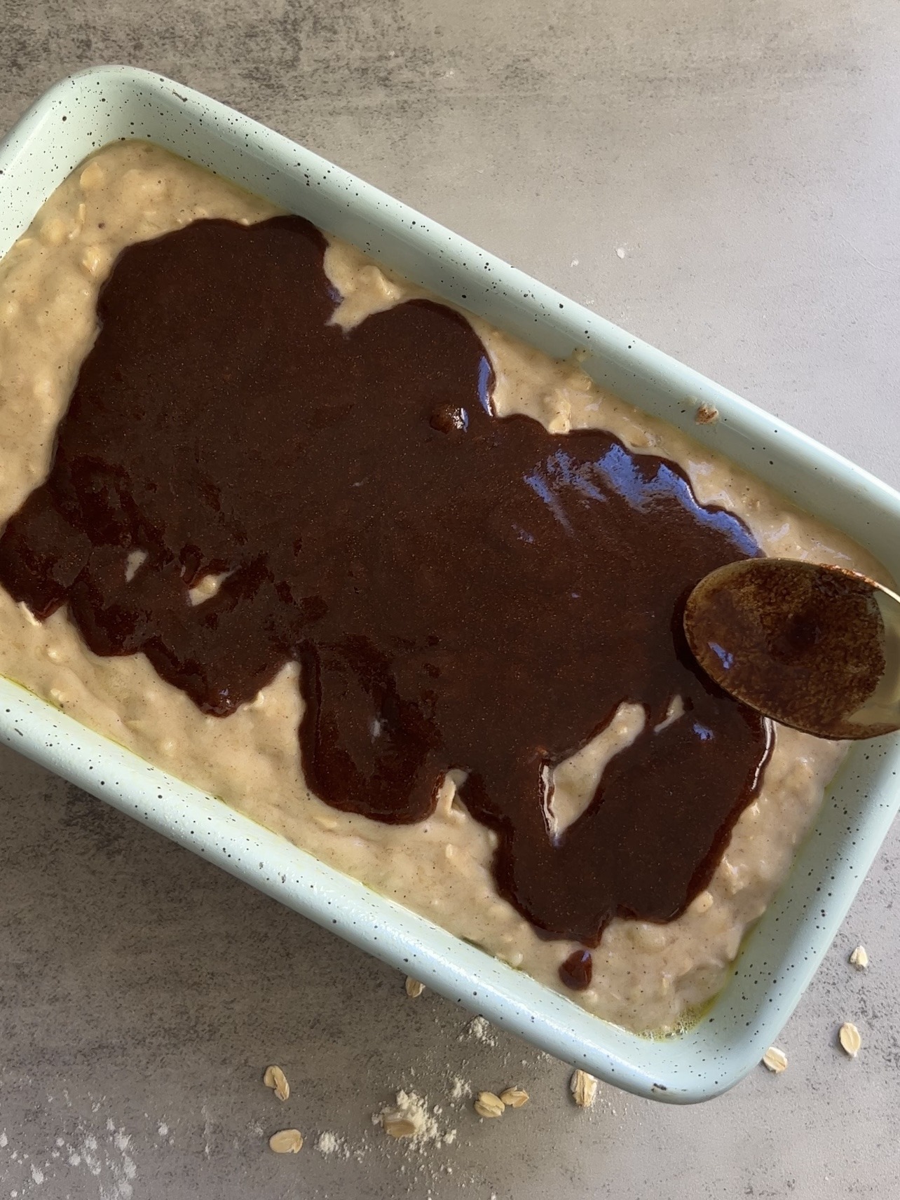 pouring the cinnamon swirl over the top of the banana bread