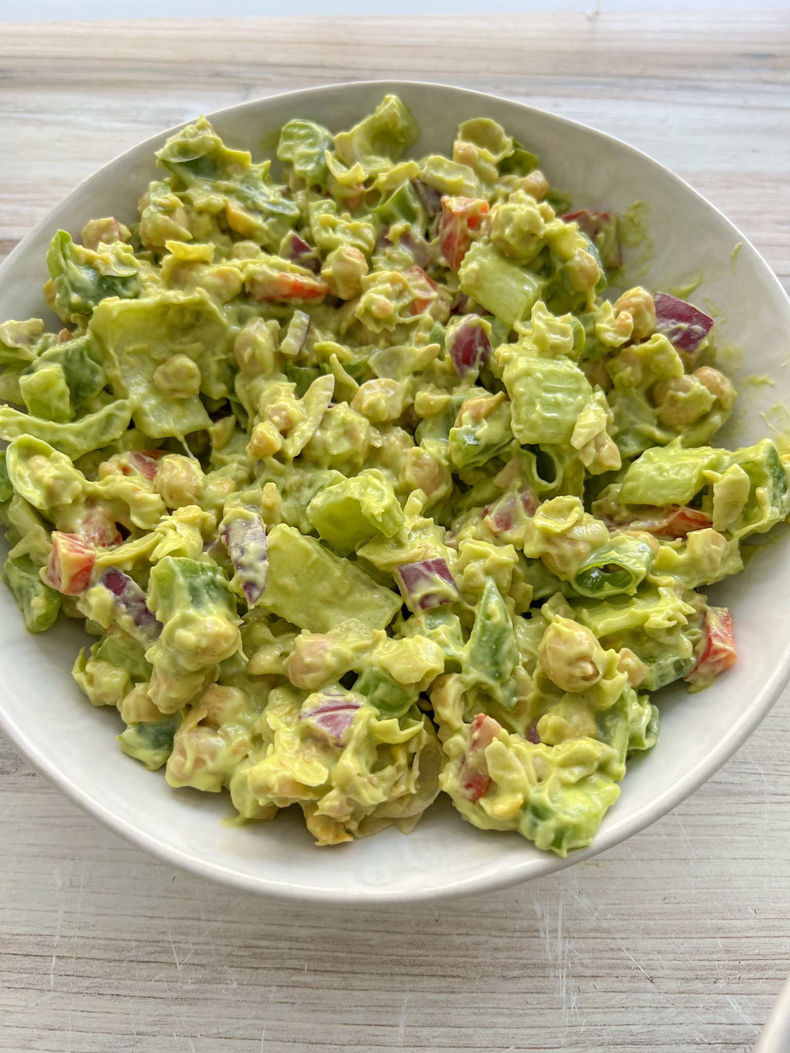 avocado chickpea tuna salad in a white bowl on a kitchen counter. 