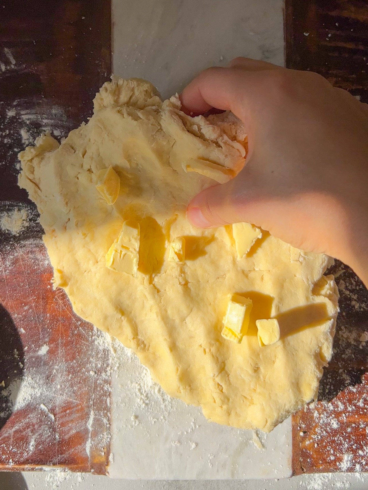 rolling the dough and kneading butter into the vegan biscuit dough