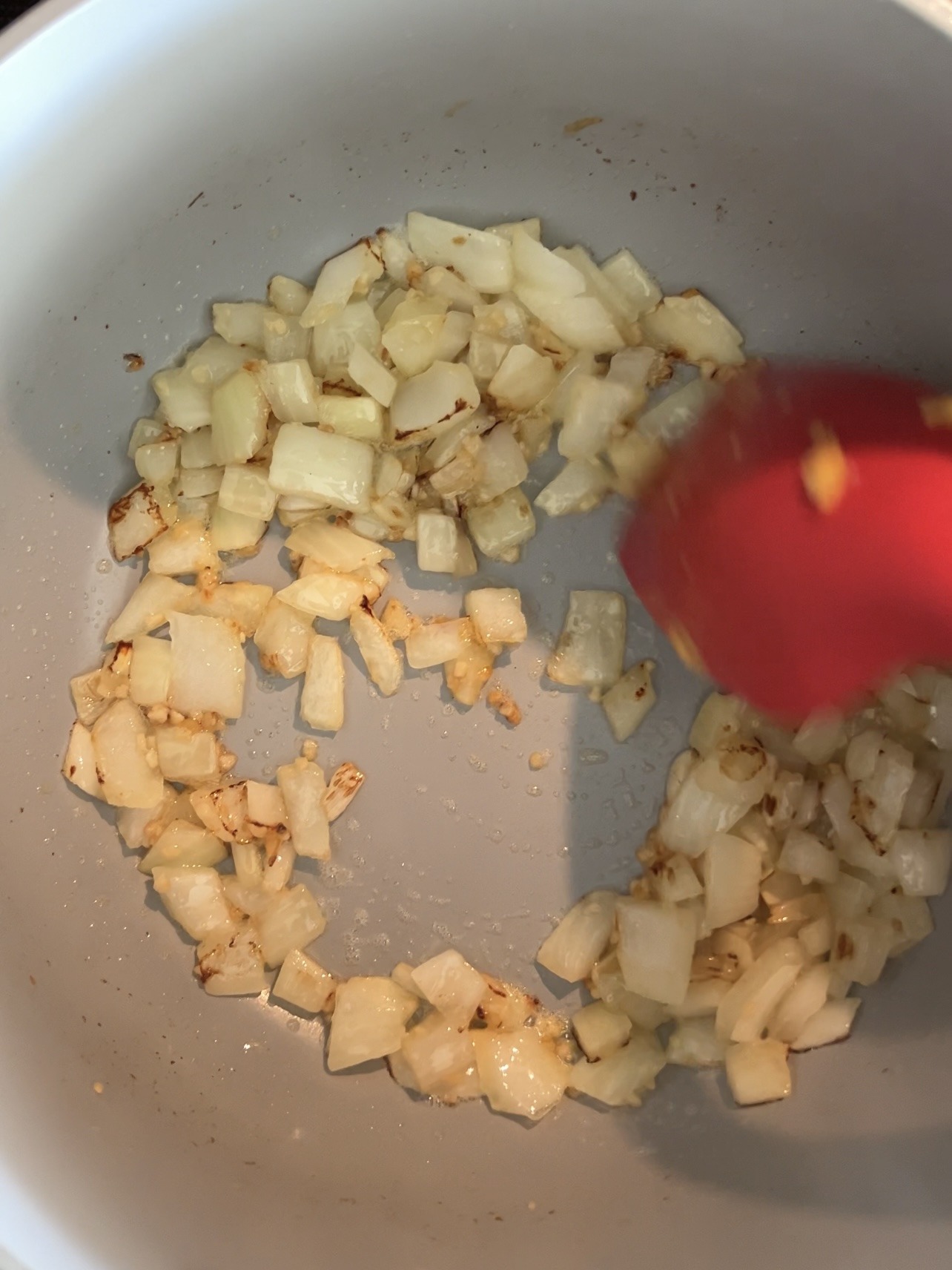 Onion and garlic being sautéed in a large pot. 