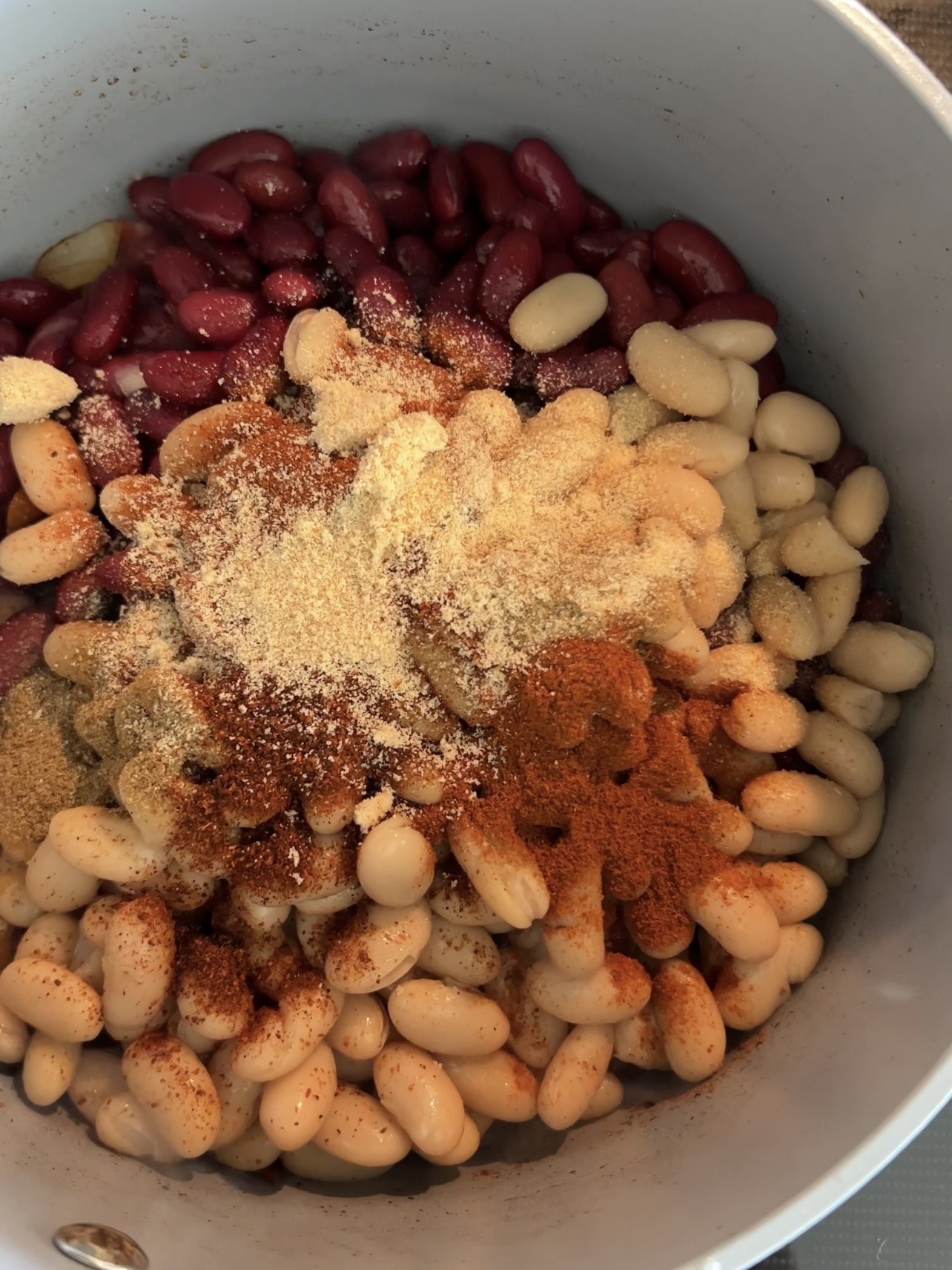 Beans and spices being added to the large pot. 