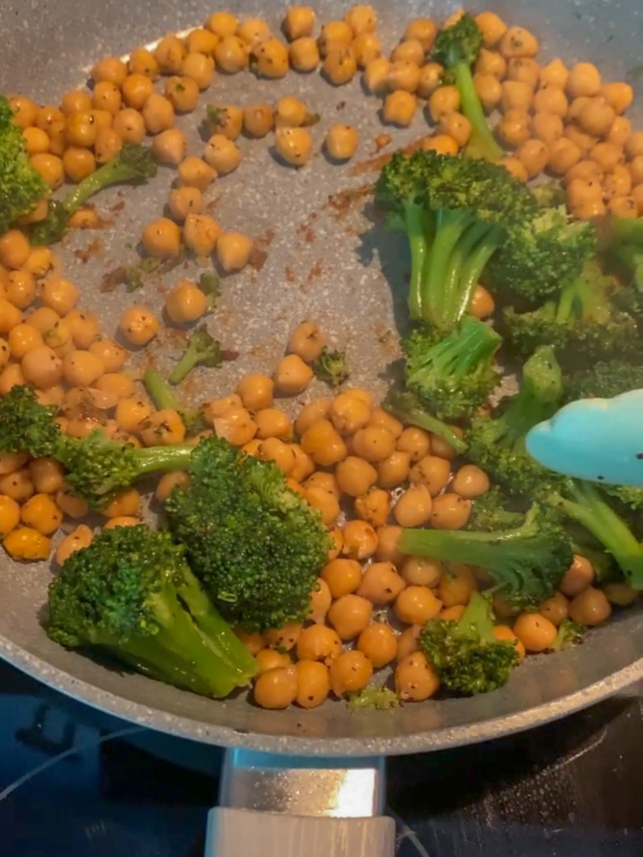 Sautéing broccoli with chickpeas in a skillet.