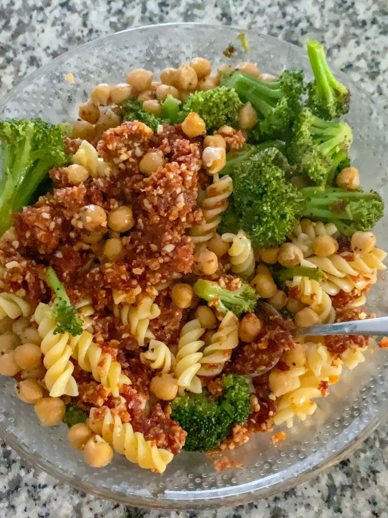 Mixing pesto with pasta and veggies.