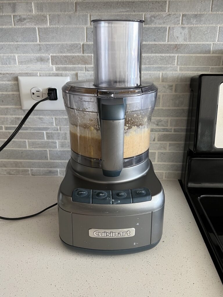 Chickpea meatball mixture in a food processor on a kitchen counter. 