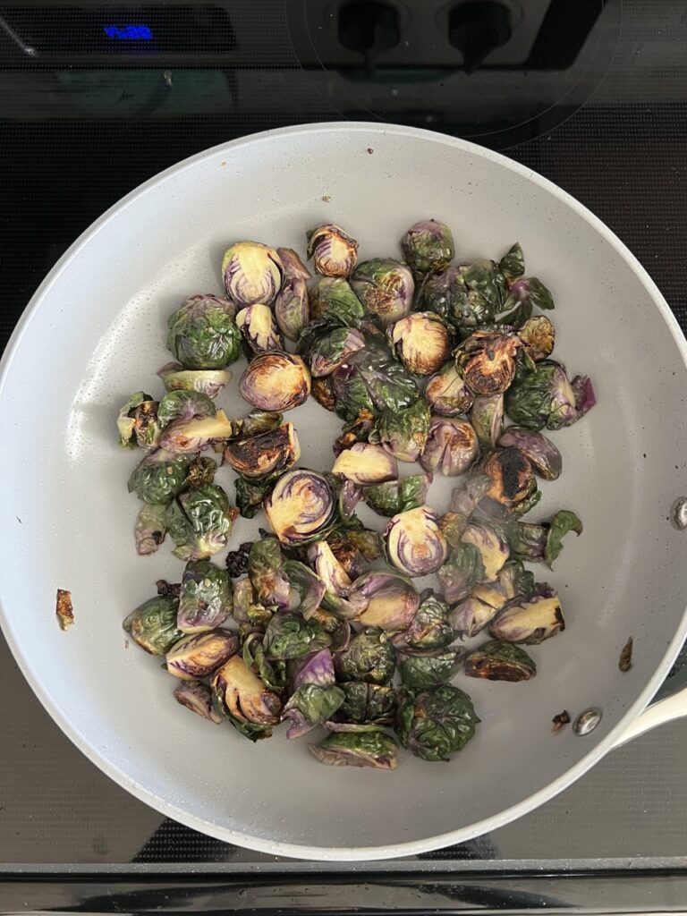 Brussels sprouts being sautéed in a pan. 