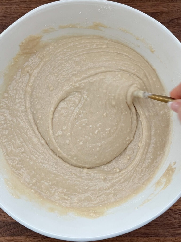 Stirring donut batter in a large bowl.