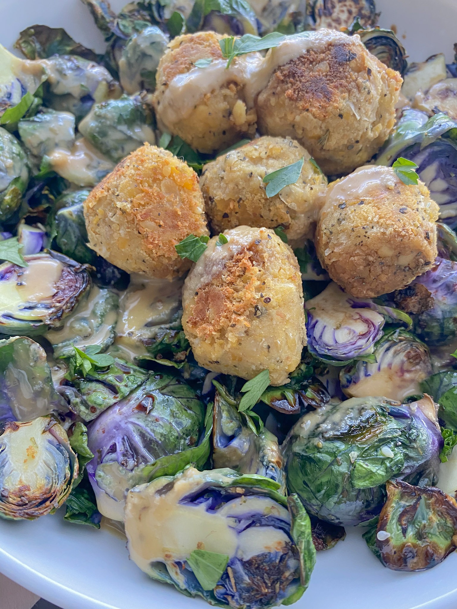 Up close shot of bed of brussels sprouts topped with chickpea meatballs. 