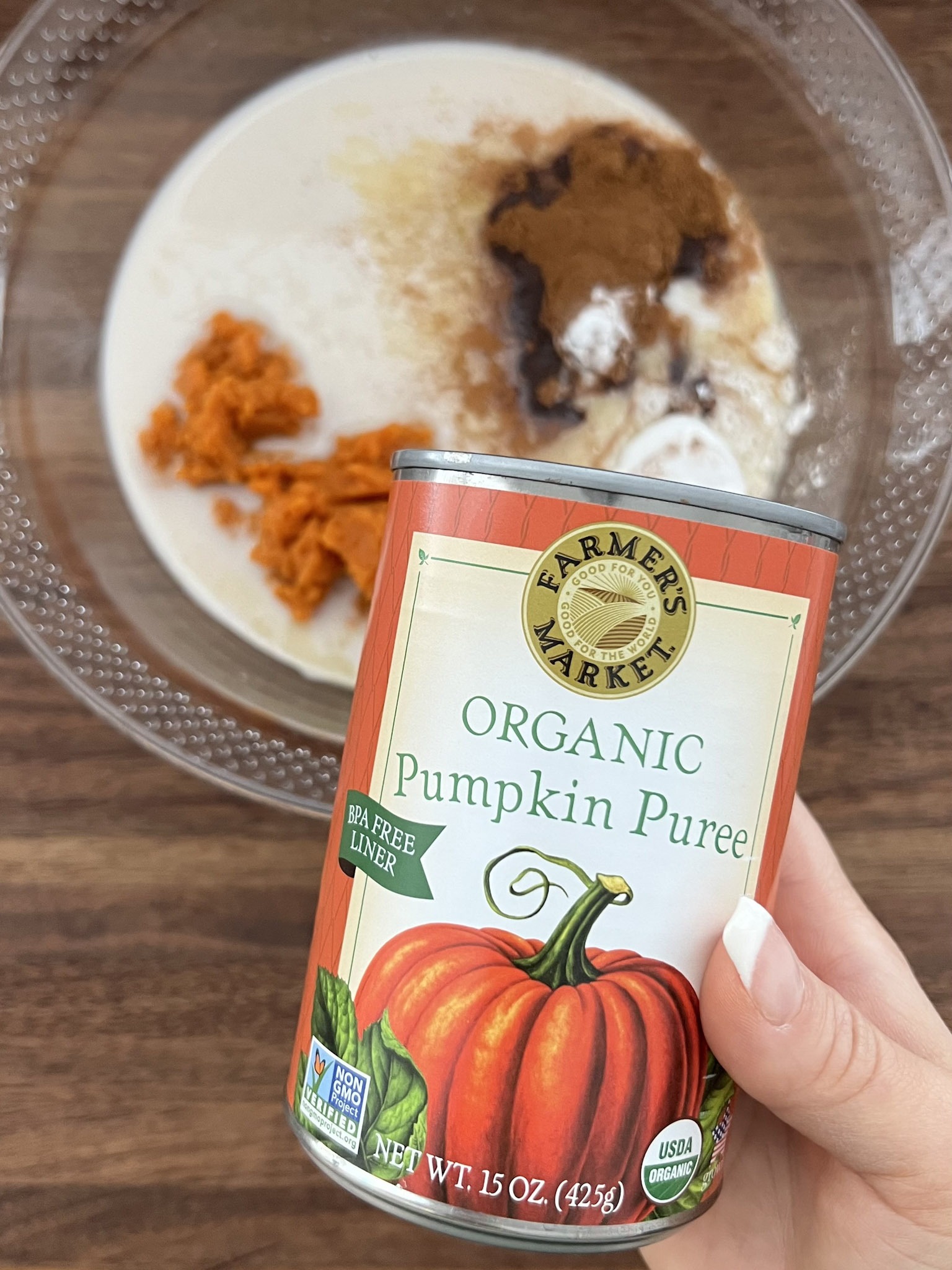 Hand holding a can of pumpkin puree.