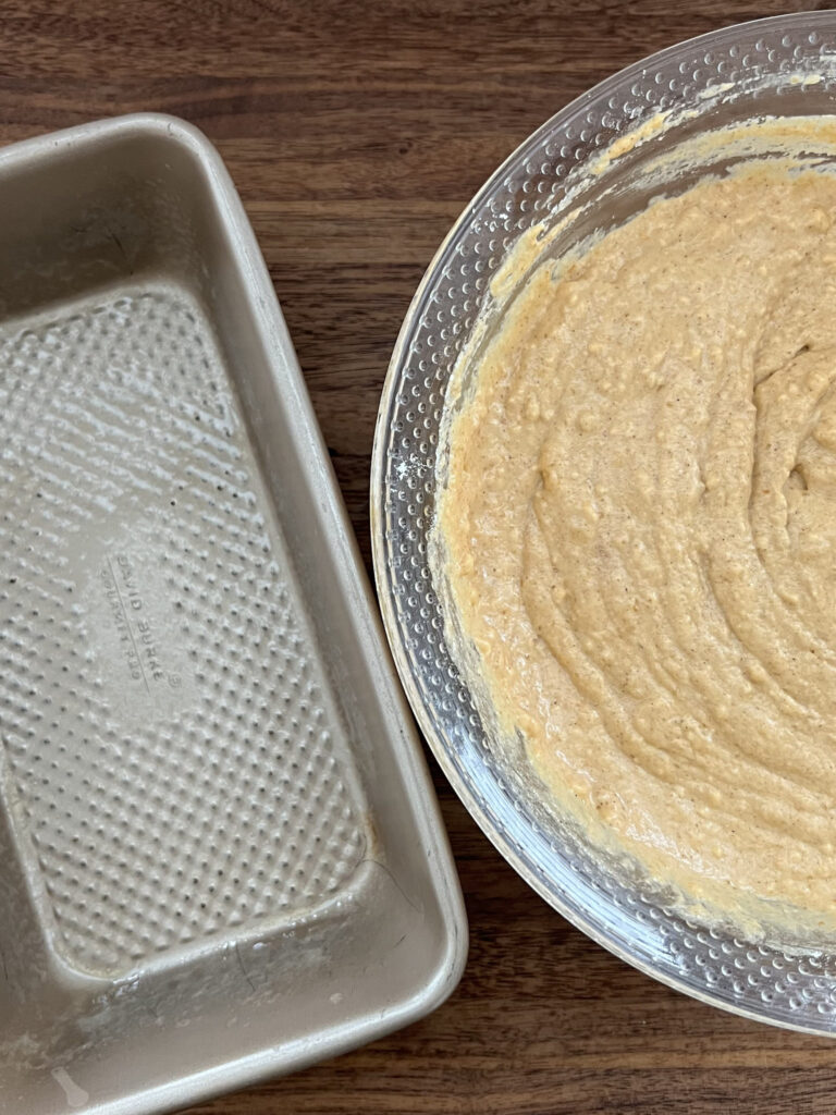 Batter in a bowl near a loaf pan.