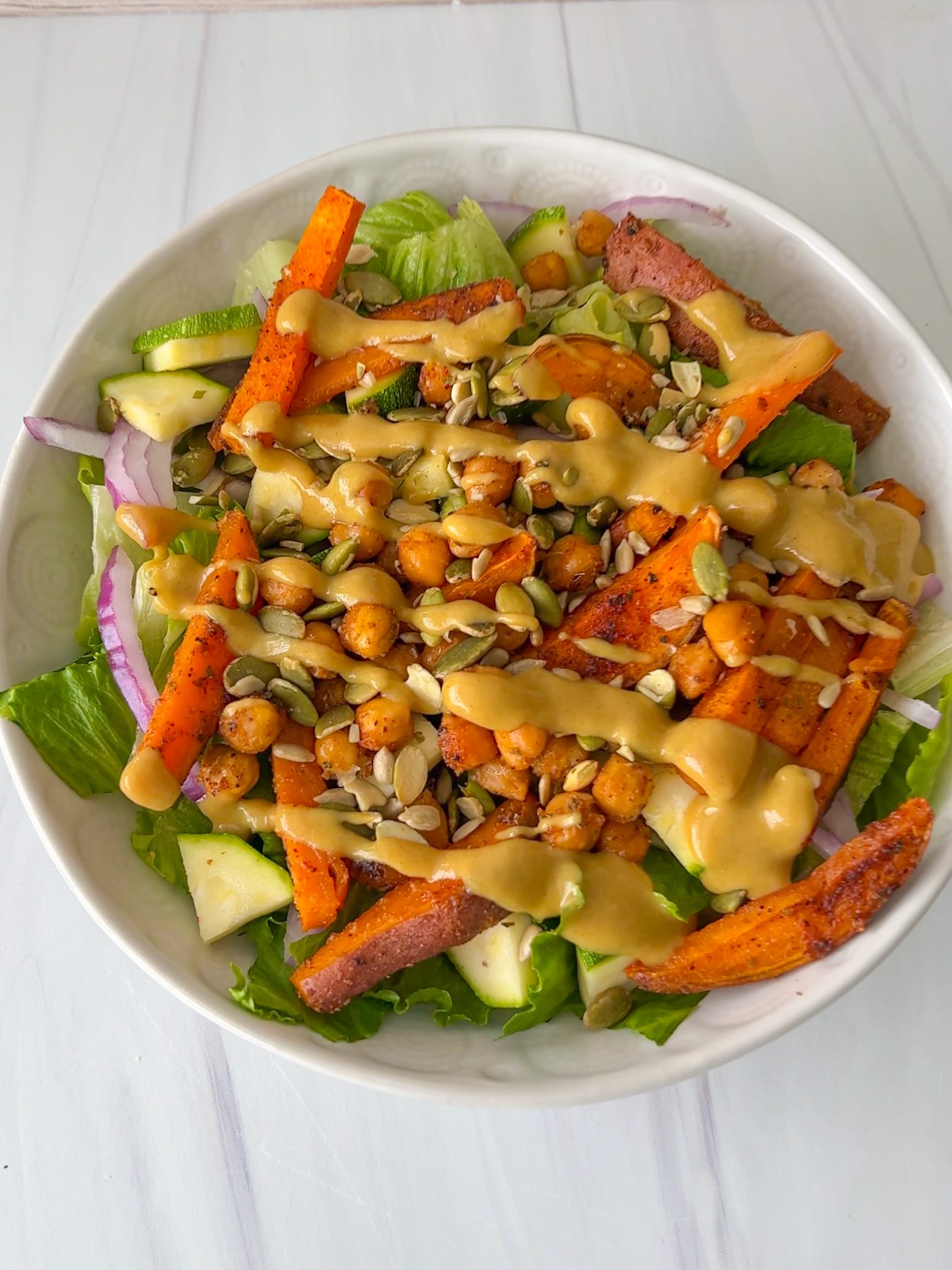 This hearty and filling salad topped with roasted sweet potatoes, crispy chickpeas, and drizzled with vegan honey mustard, is perfect any time of year. It is a great option for lunch or dinner and so easy to assemble.