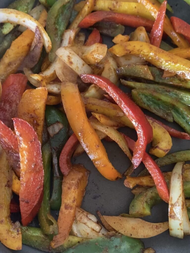 Sautéing peppers and onions in a hot pan.