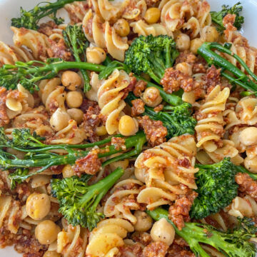 Vegan Sun-dried Tomato Pesto Pasta served with broccoli in a white bowl.