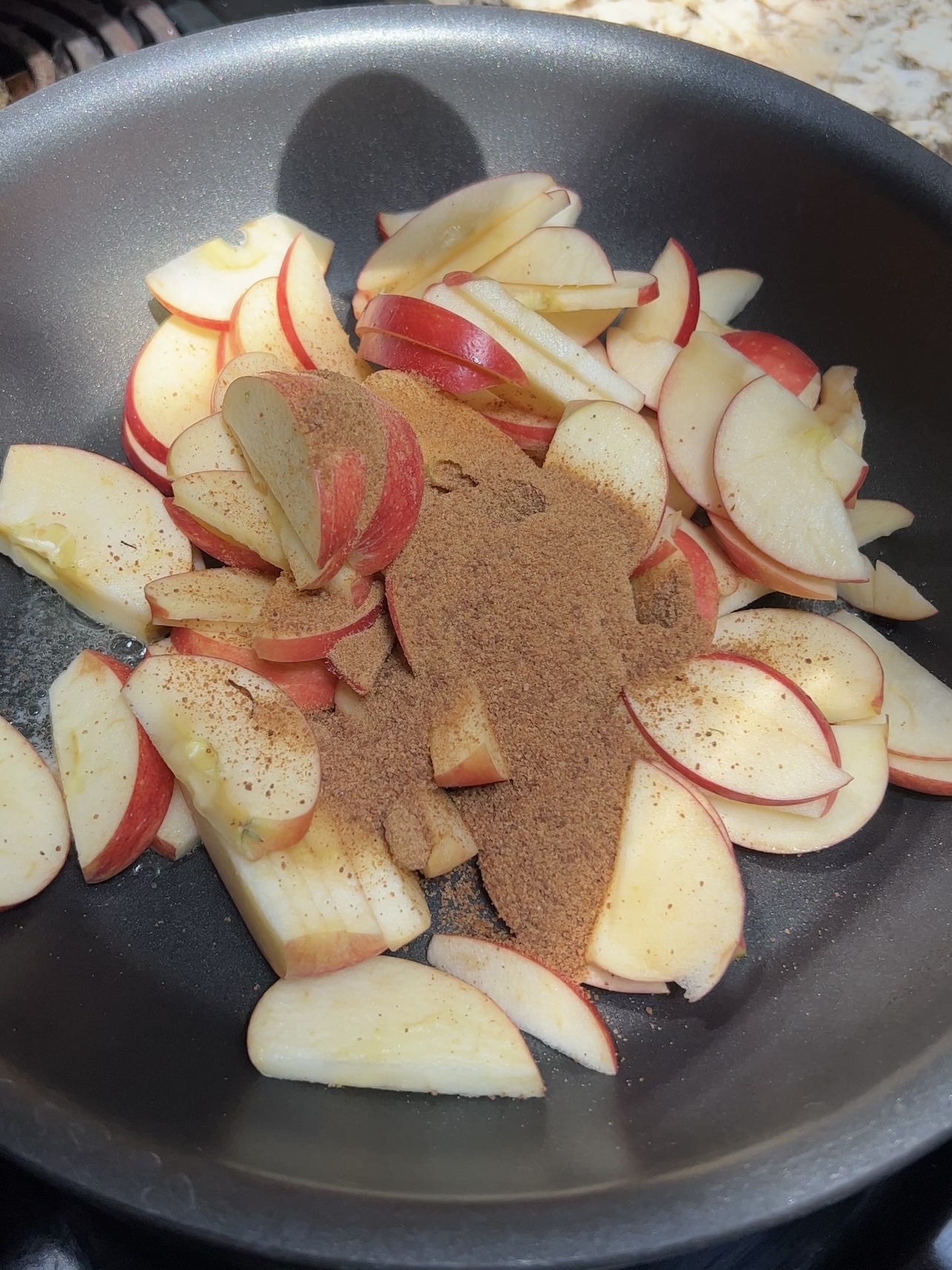 adding the apples, cinnamon, and sugar to the skillet