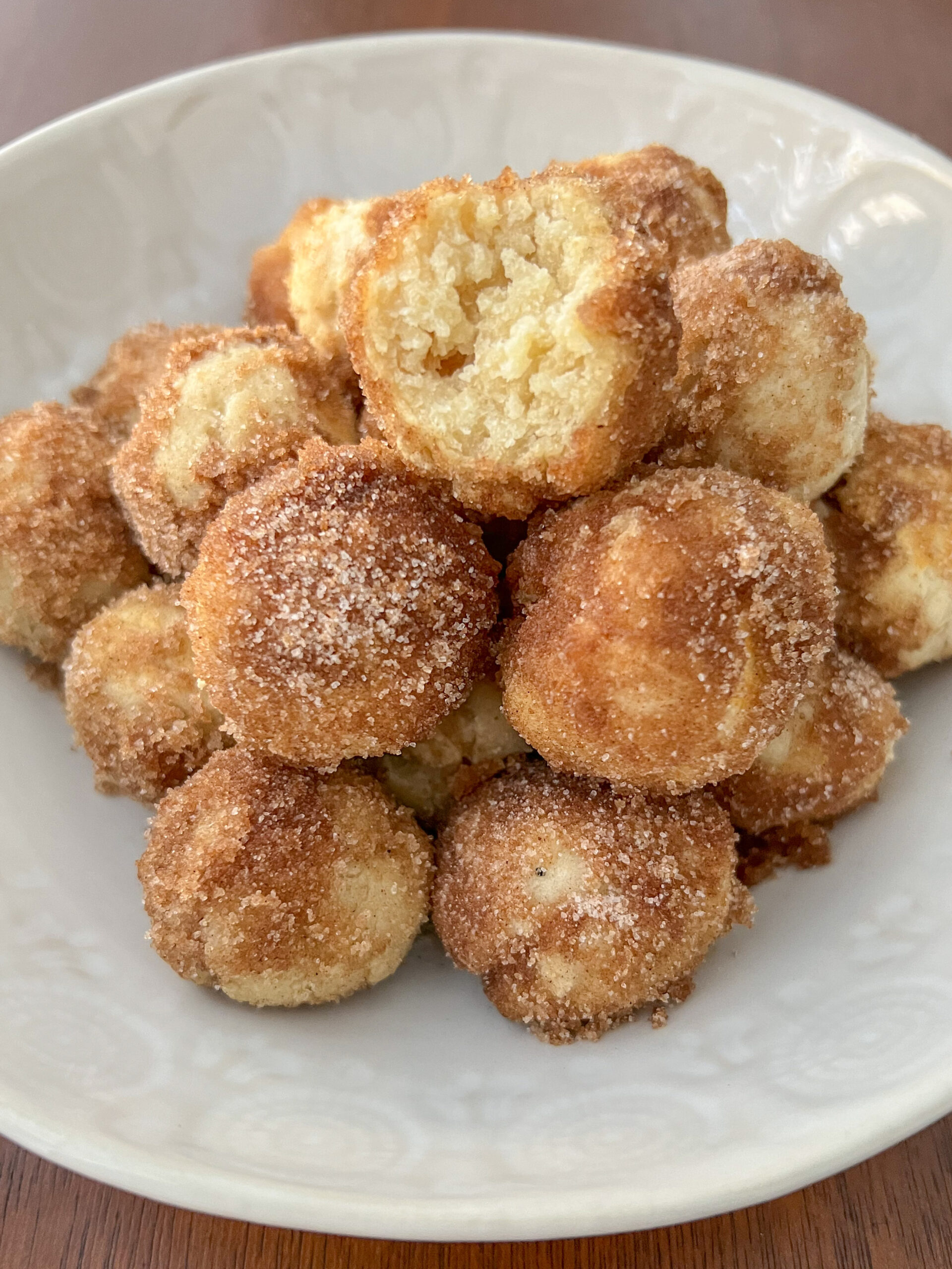 Bagel bites stacked on a white plate with the top bagel bite missing a bite. 