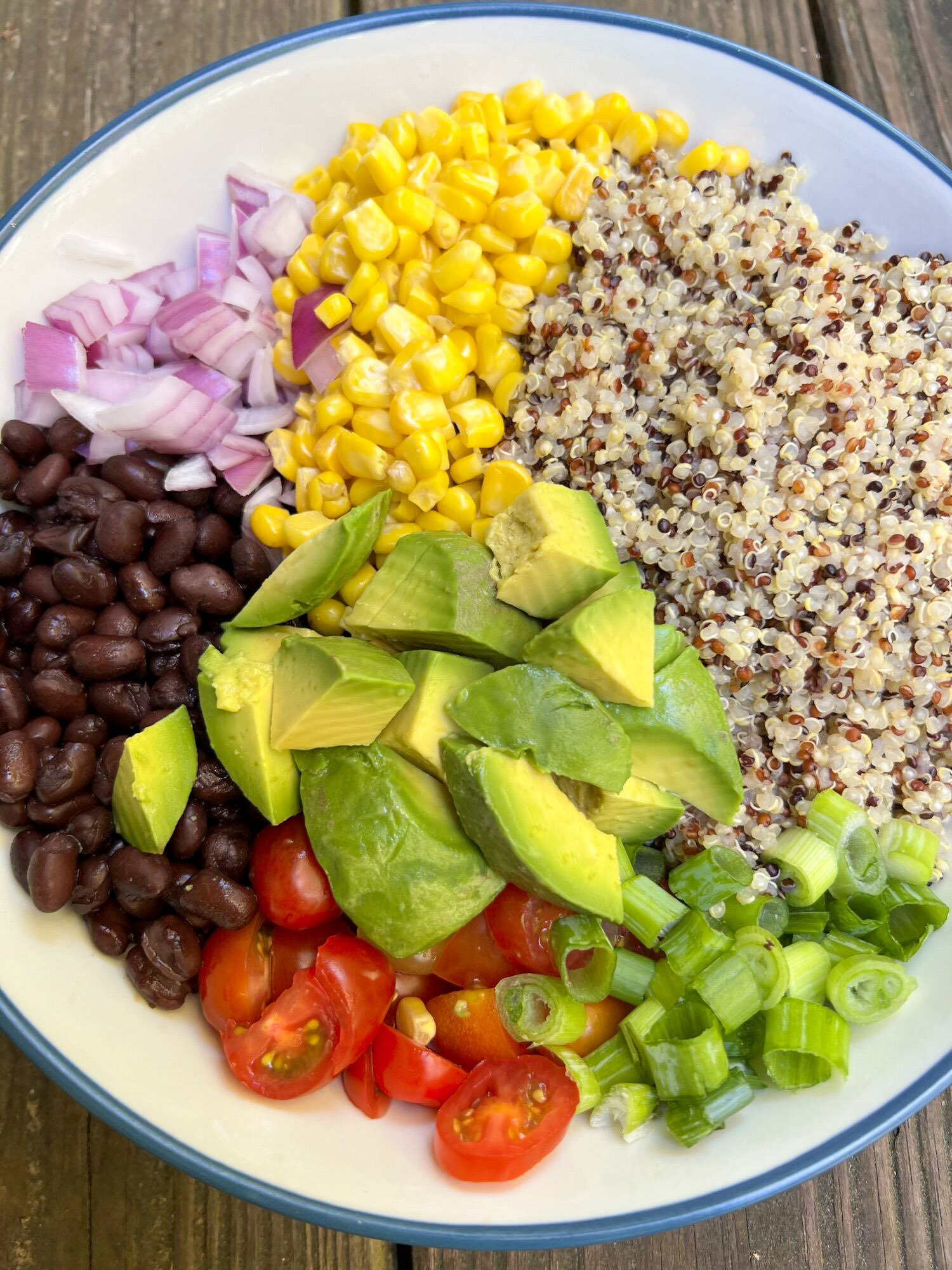 Ingredients for black bean quinoa salad in a white bowl. 