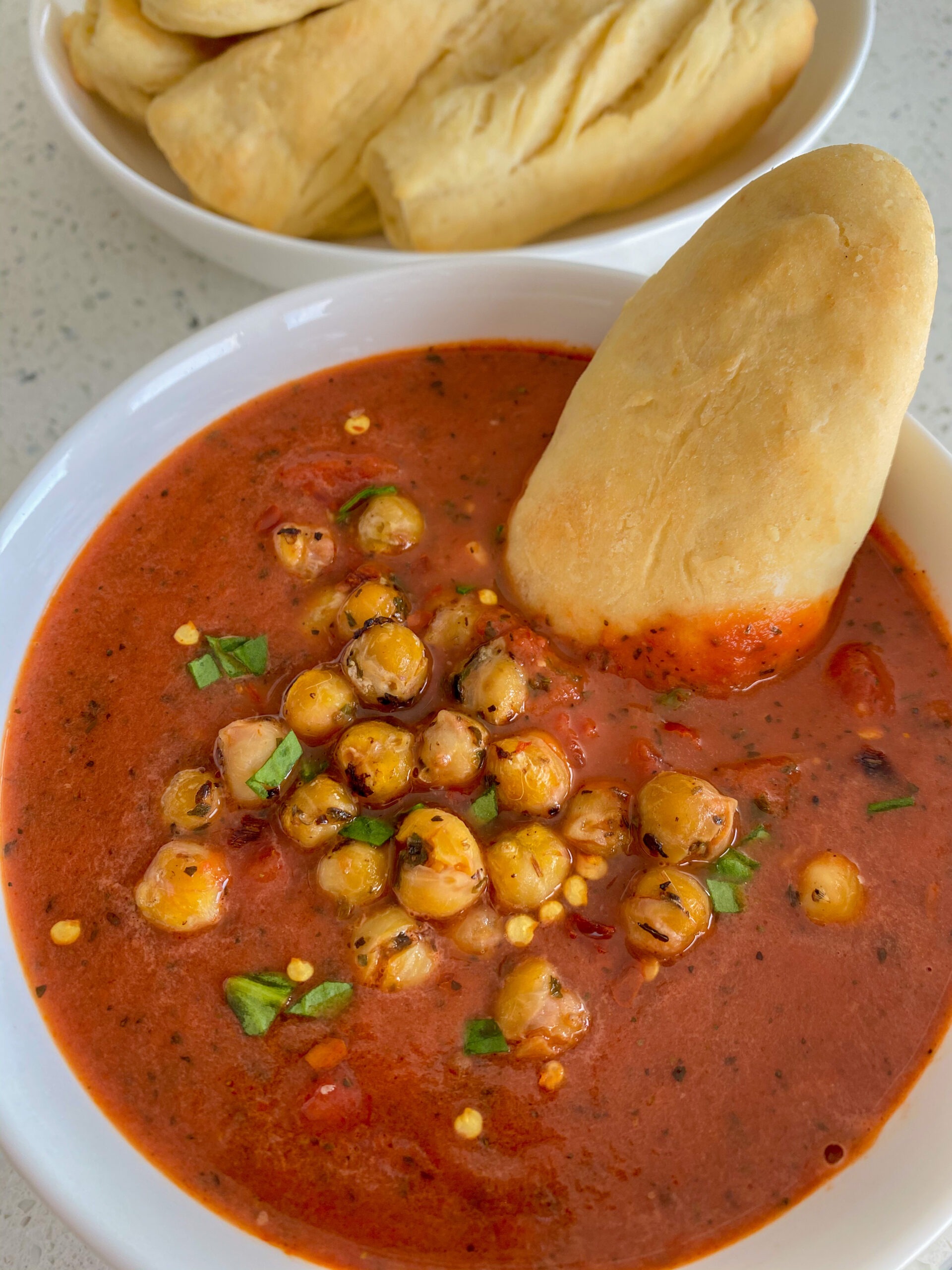 Tomato soup topped with chickpeas and served with breadsticks.