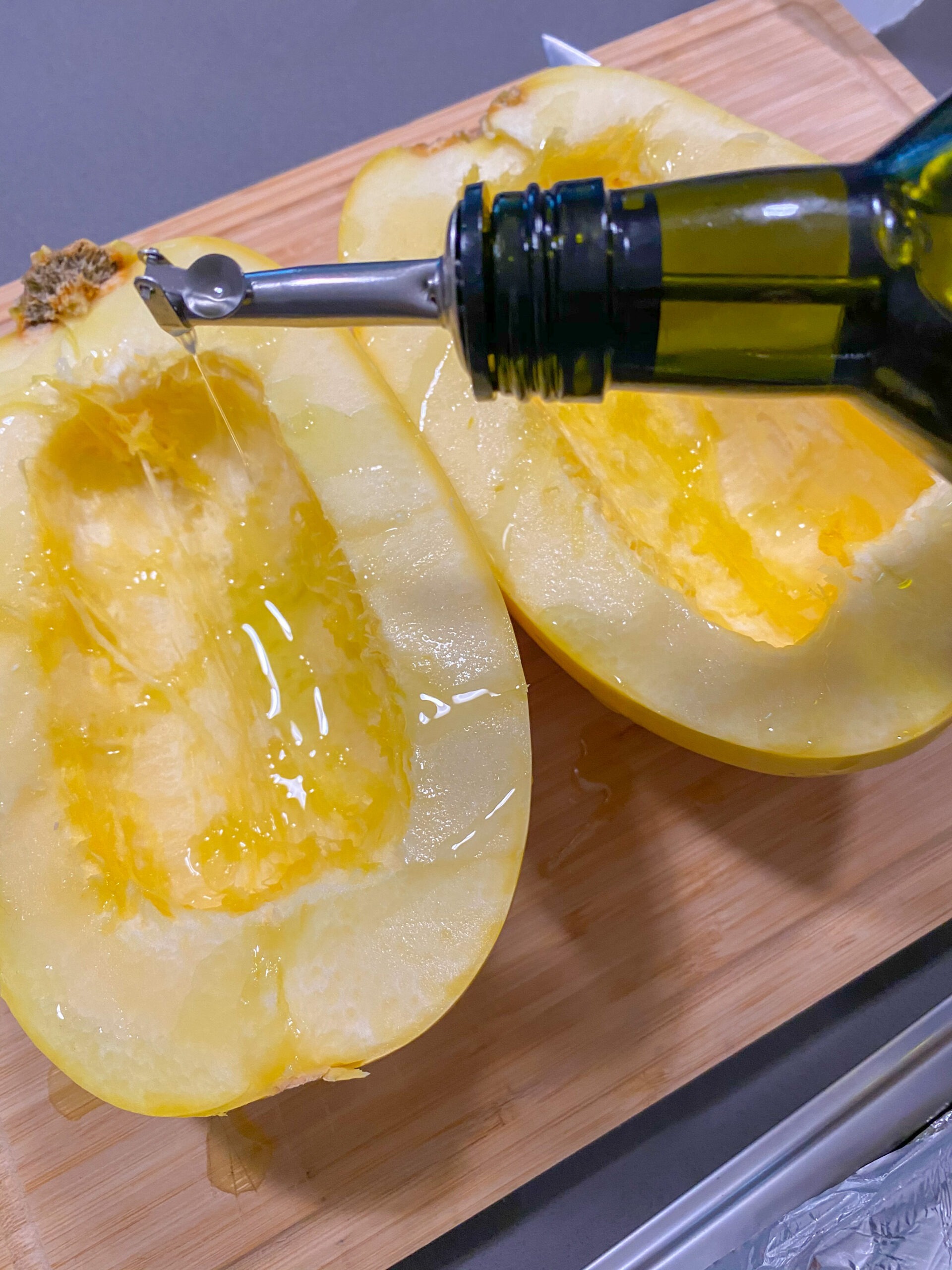 Drizzling a spaghetti squash with olive oil.