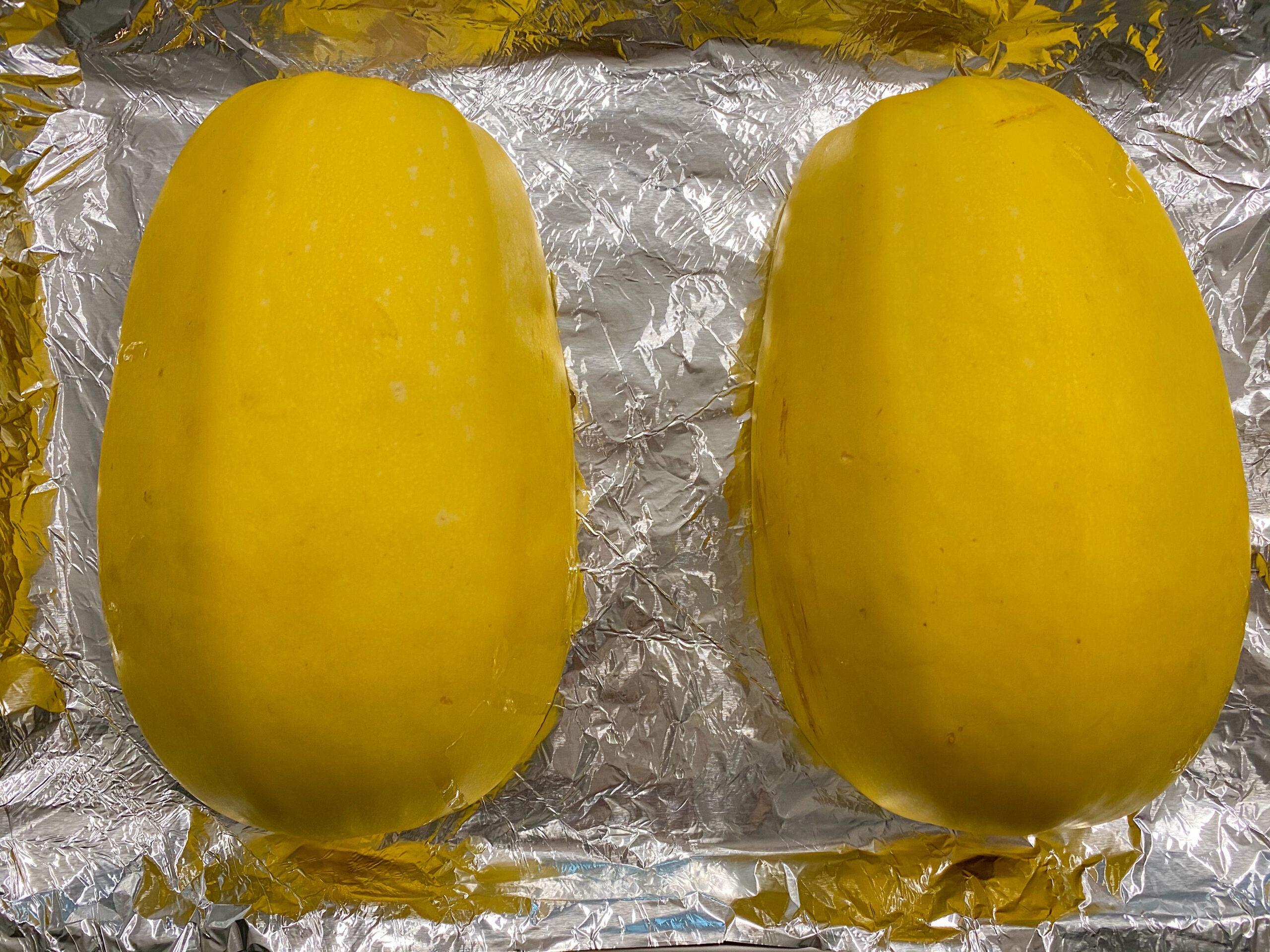 Spaghetti squash cut side down on foil.