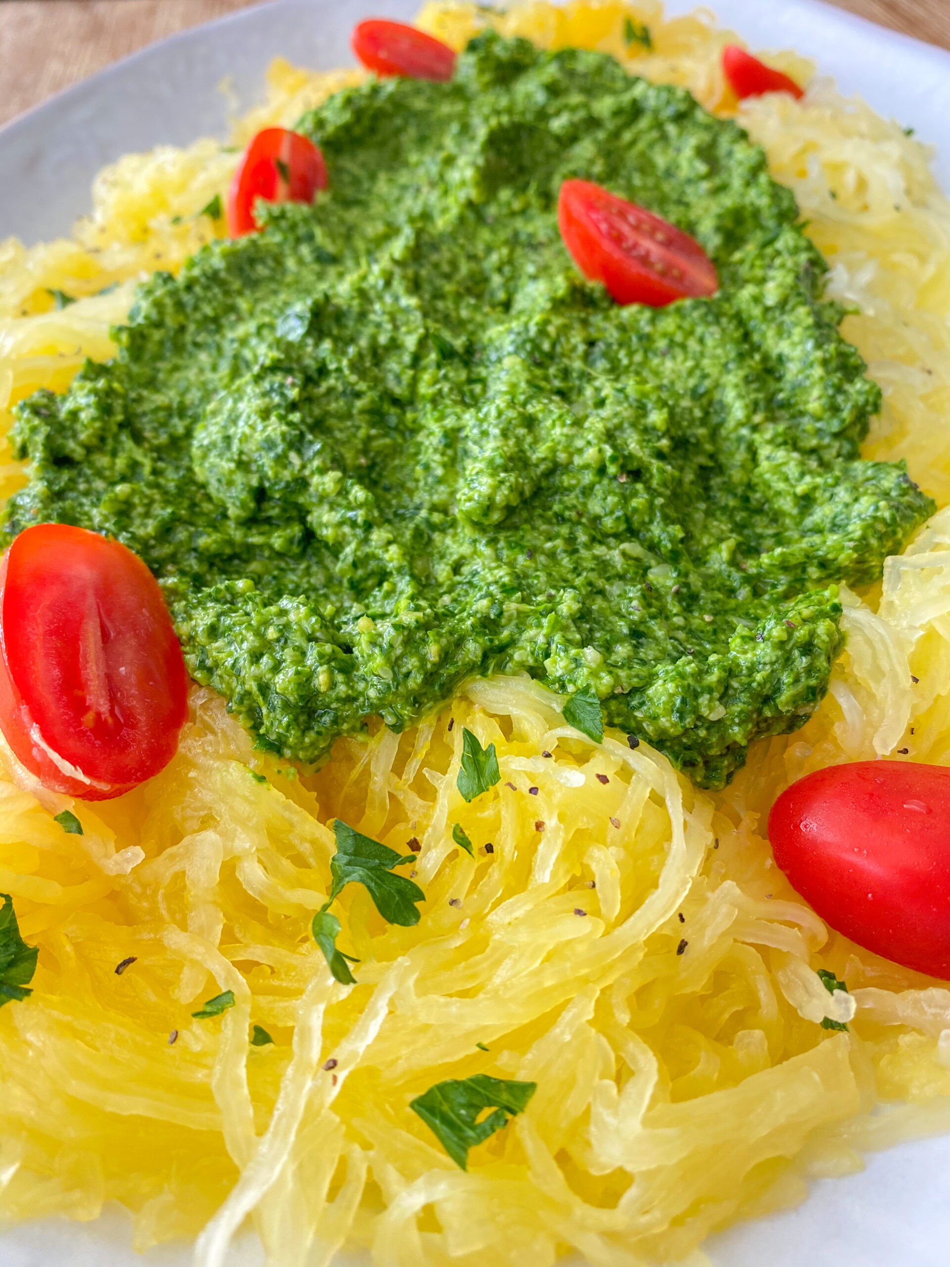 Spaghetti squash pasta topped with pesto sauce and cherry tomatoes.