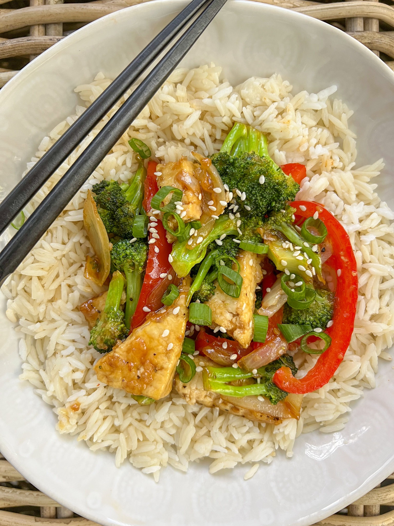 Mongolian tofu stir fry served with chopsticks over rice.