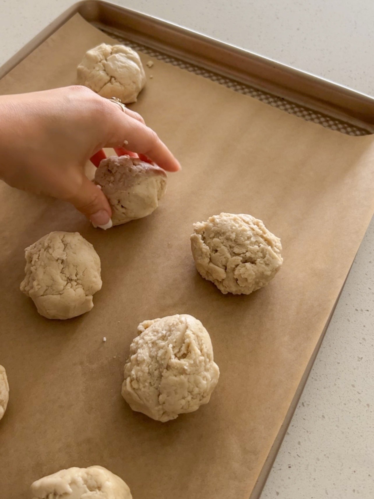 Dropping vegan biscuits onto a baking sheet pan.