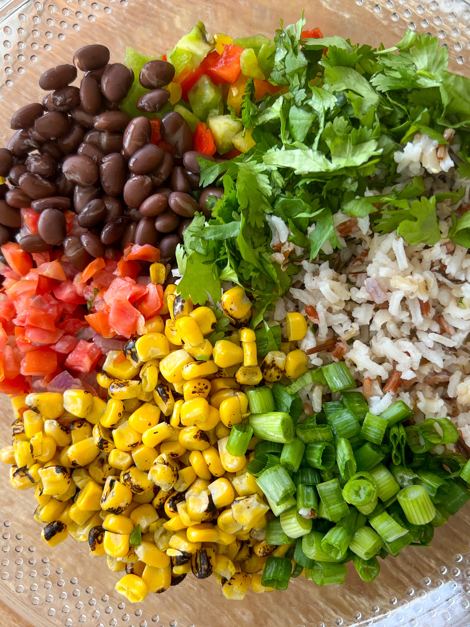 wild rice and black bean salad ingredients in a clear mixing bowl. 