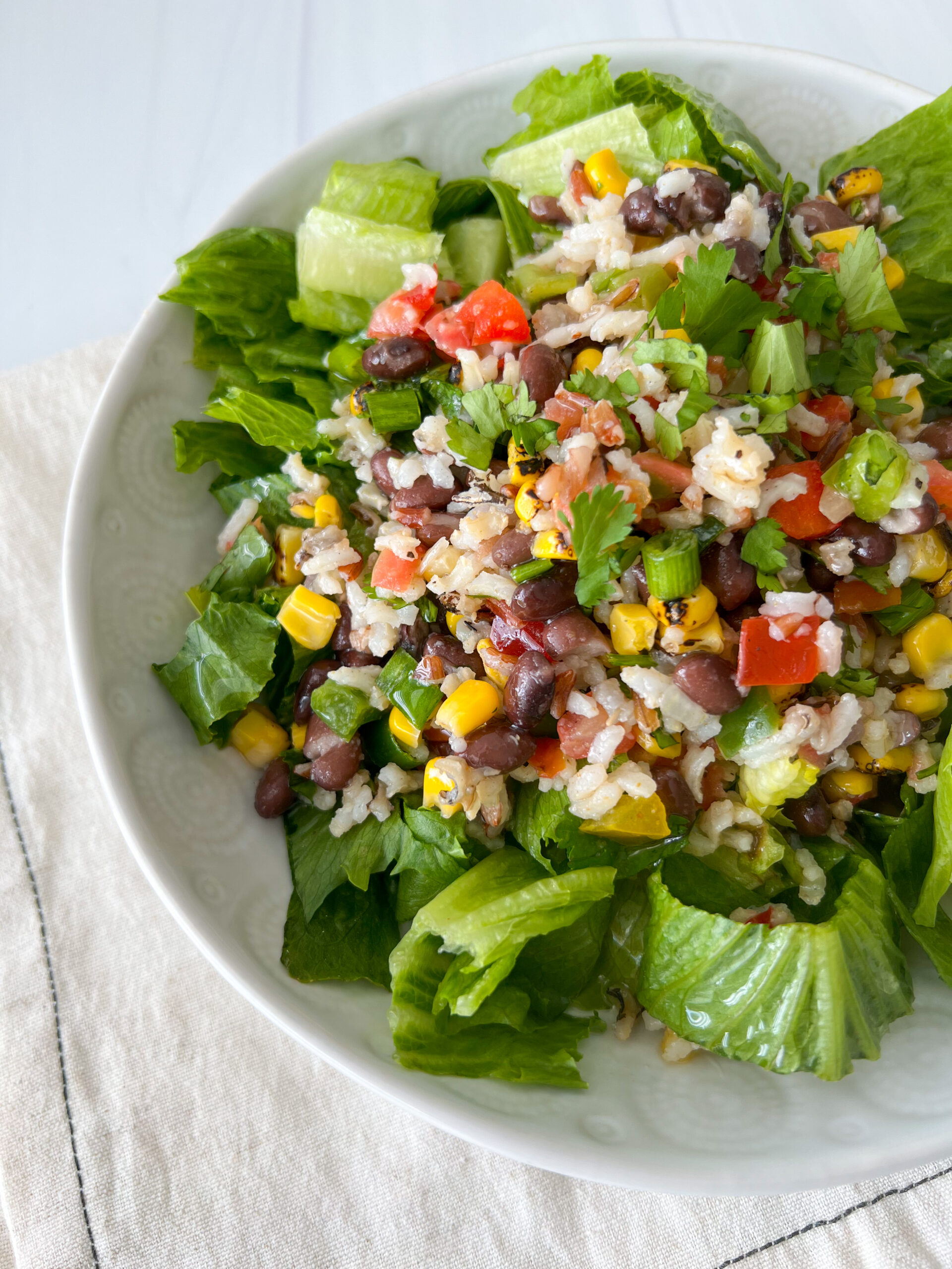 wild rice and black bean salad on a bed of lettuce in a white bowl. 