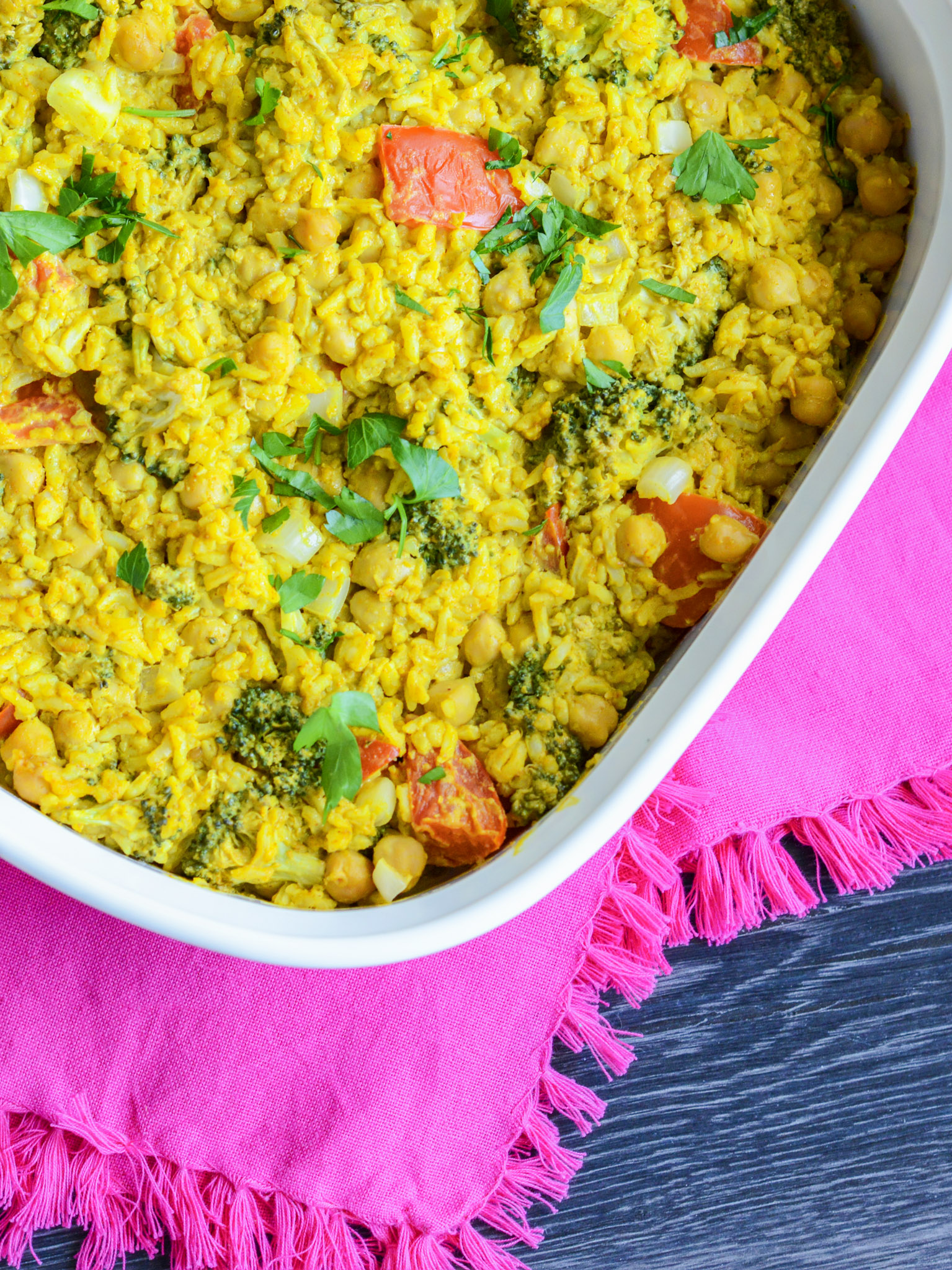 Coconut curry casserole in a white baking dish with a pink towel in the background. 