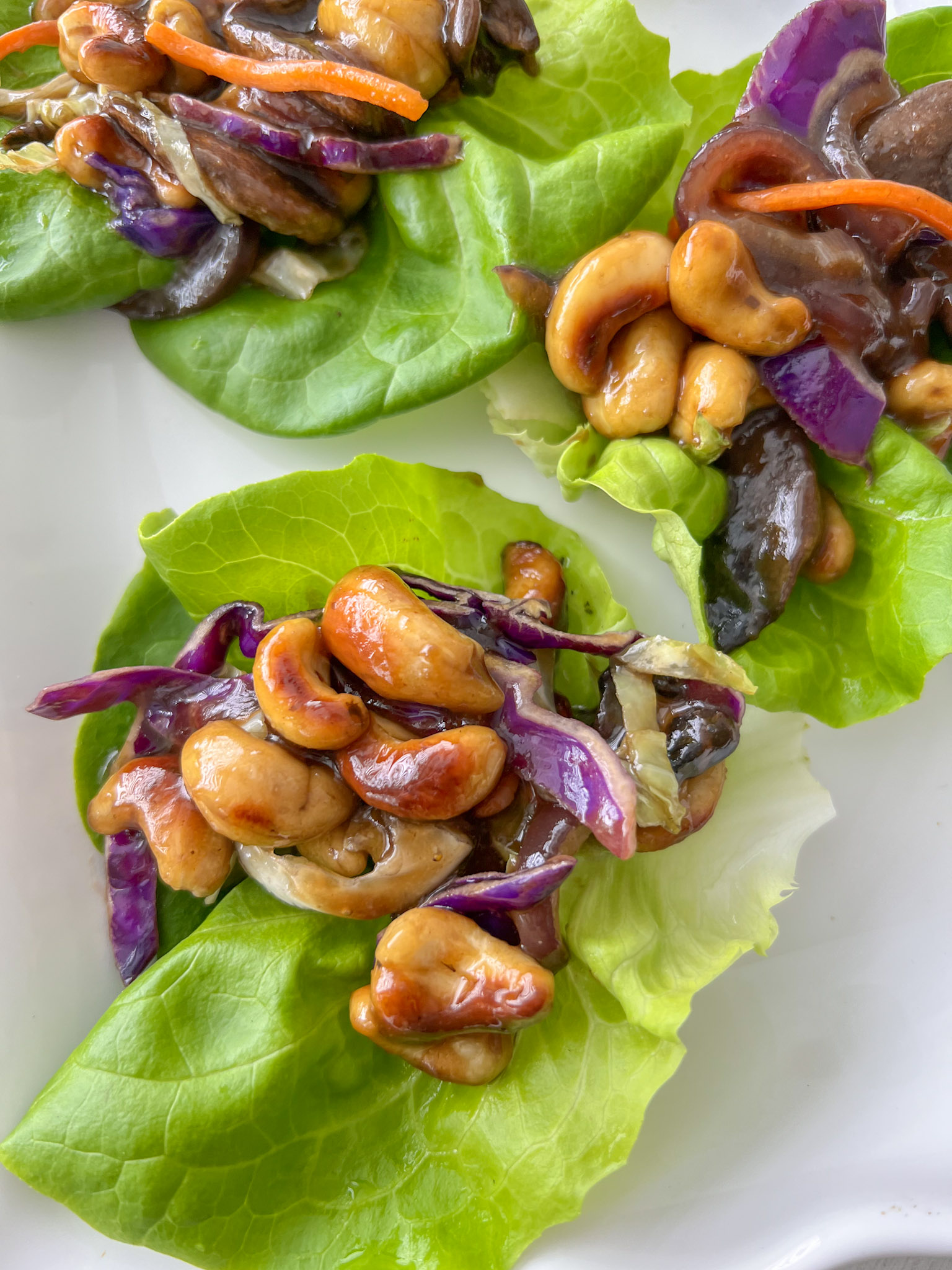 Up close shot of cashew lettuce wraps on a white plate. 