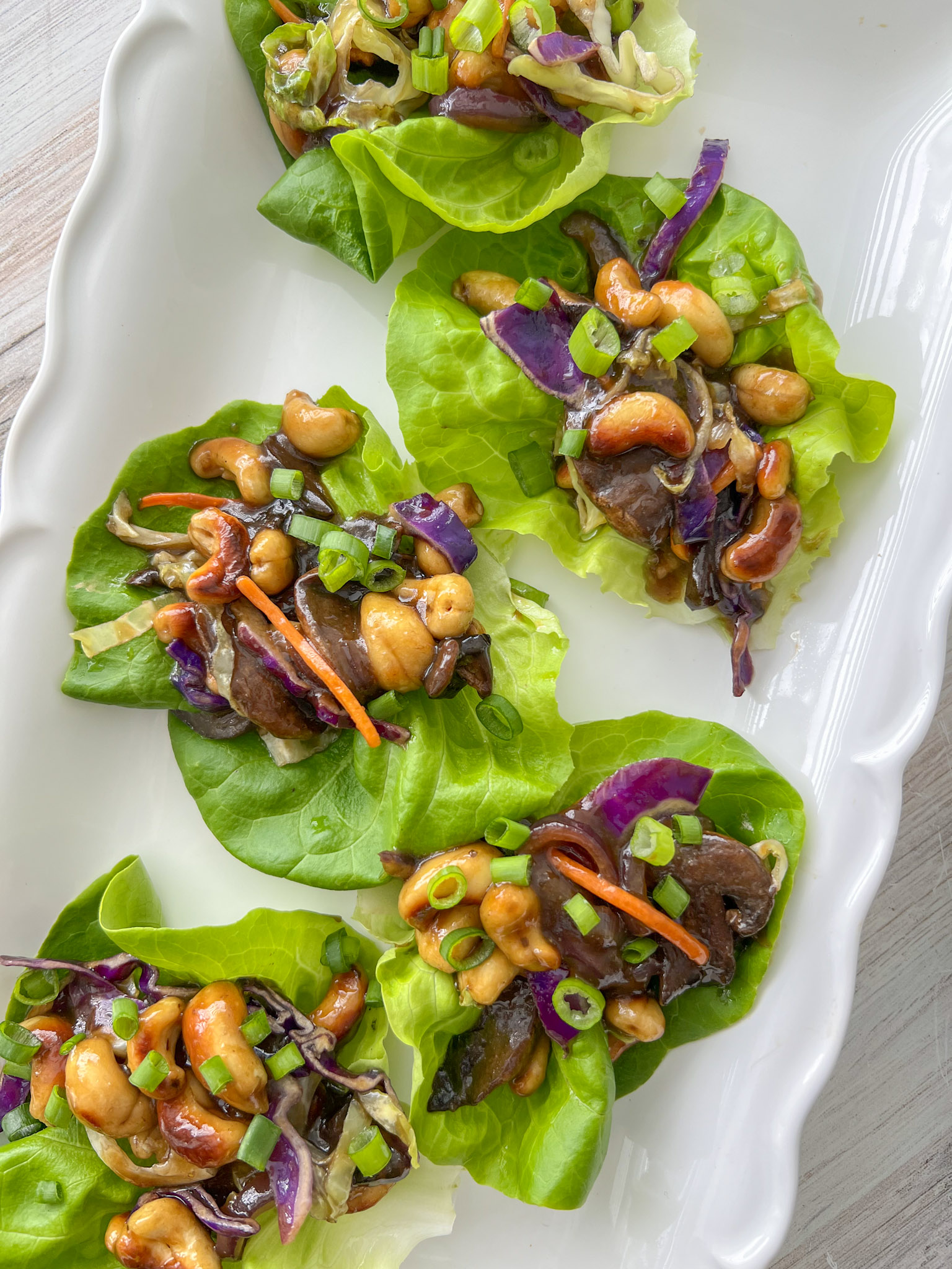 teriyaki cashew lettuce wraps lined up on a white serving platter. 