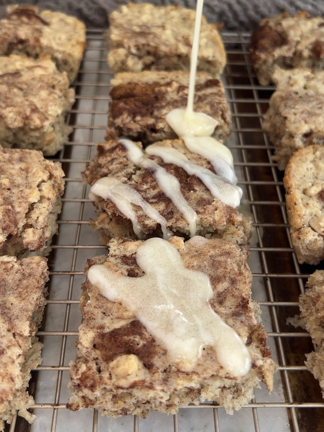 drizzling the cinnamon roll bars with cream cheese frosting