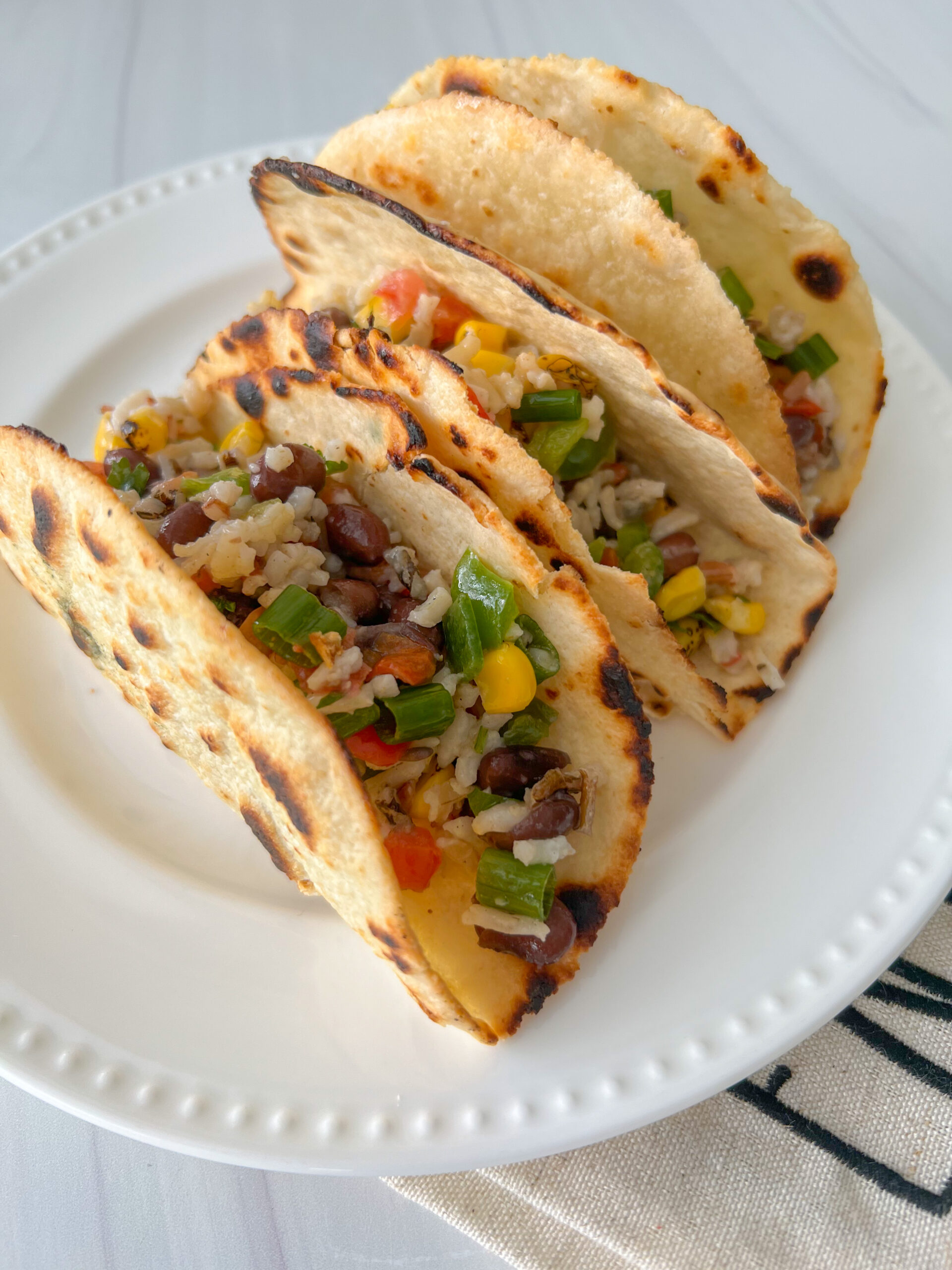 taco shells on a white plate with a mixture of rice, beans and vegetables in them. 